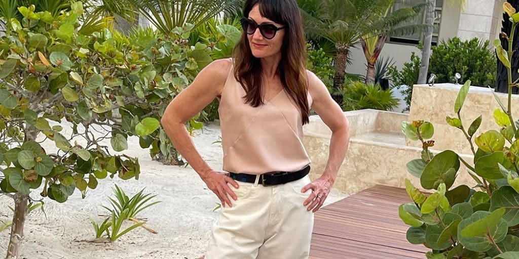 Catherine Brock, fashion blogger, wears trending outfit of white pants and rose top.